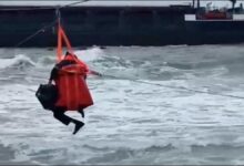 A rescuer retrieves a crew member via breeches buoy from a cargo ship grounded in Turkey.