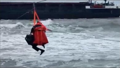 A rescuer retrieves a crew member via breeches buoy from a cargo ship grounded in Turkey.