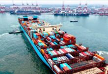 A large container ship full of stacked cargo containers sails for global shipping.