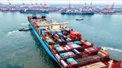 A large container ship full of stacked cargo containers sails for global shipping.