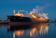 A large liquefied natural gas (LNG) carrier ship with spherical tanks sails on the ocean.