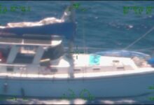 US Coast Guard personnel board the white yacht Soulmate in open water.