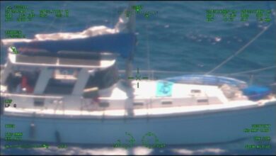 US Coast Guard personnel board the white yacht Soulmate in open water.