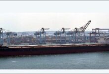 The bulk carrier Pacific Century navigates near a port wharf.