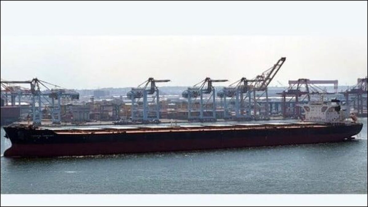 The bulk carrier Pacific Century navigates near a port wharf.