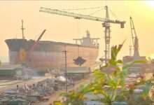 Industrial workers begin dismantling a large cargo ship at a busy recycling yard.