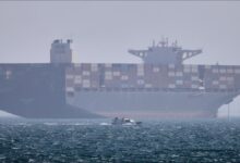 A large container ship sails, representing global shipping and geopolitical tensions in trade routes.