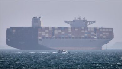 A large container ship sails, representing global shipping and geopolitical tensions in trade routes.