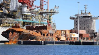 A large cargo ship is being dismantled for scrap on a dry dock, illustrating vessel demolition.
