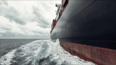 Large cargo ship hull, partially submerged, featuring advanced fouling control coatings for efficiency.