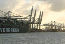 A large container ship sails a busy waterway, connecting to the Port of Rotterdam.