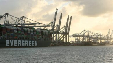 A large container ship sails a busy waterway, connecting to the Port of Rotterdam.