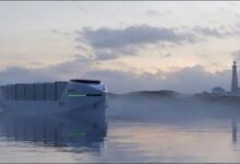 A modern electric battery-powered container vessel sailing on calm water.