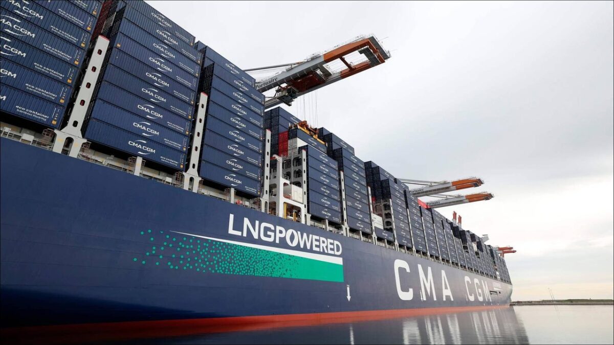 A large CMA CGM container ship is docked at a port terminal, loaded with containers.