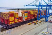 A large container ship docked at a busy port, representing JAXPORT's expanded global services.