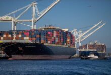 A large dry bulk carrier ship sails on the water, representing global shipping.