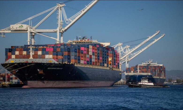 A large dry bulk carrier ship sails on the water, representing global shipping.