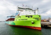 Large ship sails past an offshore wind farm, illustrating sustainable Dutch maritime efforts.