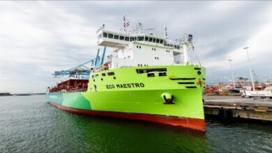 Large ship sails past an offshore wind farm, illustrating sustainable Dutch maritime efforts.