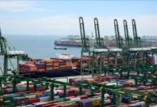 Aerial view of Singapore's Tuas Mega Port with numerous container ships and cranes.