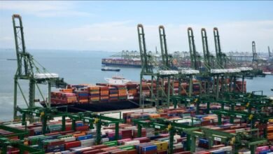 Large container ship docked at a busy port with multiple cranes loading cargo.
