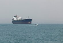 A large cargo ship navigates vital shipping lanes, representing Strait of Hormuz tensions.