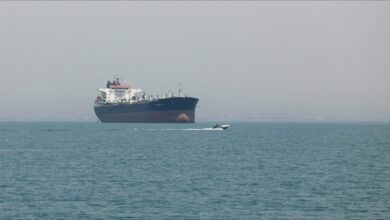 A large cargo ship navigates vital shipping lanes, representing Strait of Hormuz tensions.