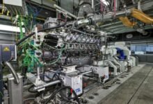 A Rolls-Royce methanol marine engine on a testbench, with a technician observing.