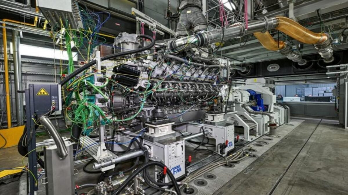 A Rolls-Royce methanol marine engine on a testbench, with a technician observing.