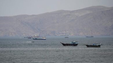 A large oil tanker navigates a strait with land visible on the horizon.