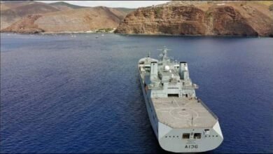A large Royal Fleet Auxiliary vessel with crew members on deck at sea.