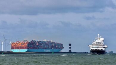 A large Maersk container ship docked at a busy port.