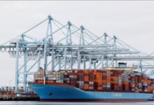 A large container ship and stacked containers at a busy US West Coast port.