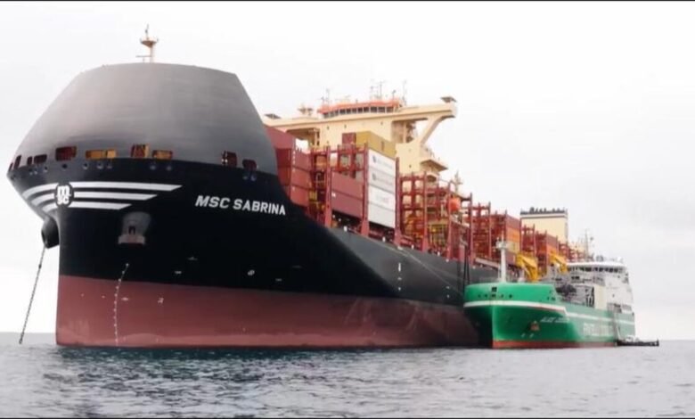 Shell LNG bunkering vessel fueling a cargo ship at a port.