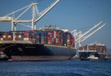 A heavily loaded container ship transports stacked cargo containers across the sea.