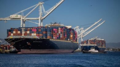 A heavily loaded container ship transports stacked cargo containers across the sea.