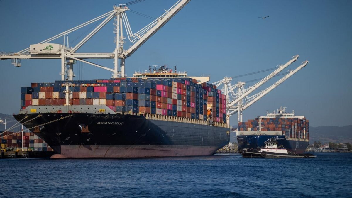 A heavily loaded container ship transports stacked cargo containers across the sea.
