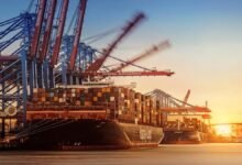 Large container ship laden with cargo sails, representing global shipping.