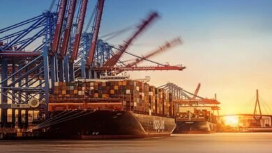 Large container ship laden with cargo sails, representing global shipping.