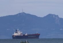 A large oil tanker ship sails on blue ocean waters under a clear sky.