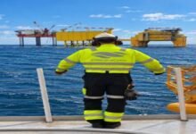 An offshore supply vessel with cranes and personnel on deck, supporting specialized operations.