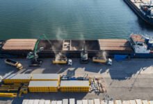 A large cargo ship with cranes docked at a port for heavy lift operations.
