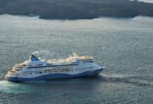 A white Celestyal cruise ship sails across the blue Mediterranean Sea.