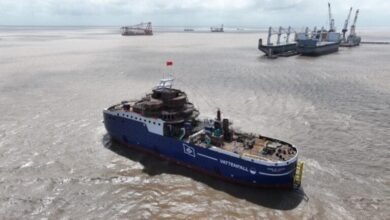 The blue-hulled Wind of Ocean Service Operation Vessel sails past offshore wind turbines.