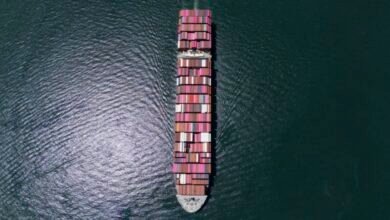 A large container ship navigates open waters, symbolizing global trade and maritime activity.