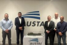 Kongsberg and Austal executives shaking hands at a deal signing with Australian flags.