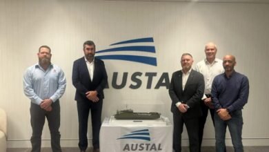Kongsberg and Austal executives shaking hands at a deal signing with Australian flags.