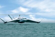 A large commercial ground effect vehicle flies low over a rough, open ocean.