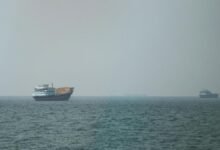 Damaged oil tanker with smoke rising in the Strait of Hormuz.
