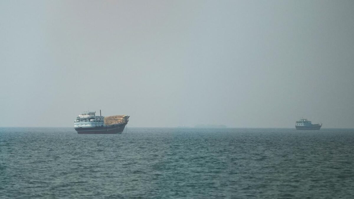 Damaged oil tanker with smoke rising in the Strait of Hormuz.